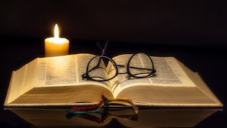 Don de ciencia. Biblia abierta con lentes encima y una vela encendida a un lado